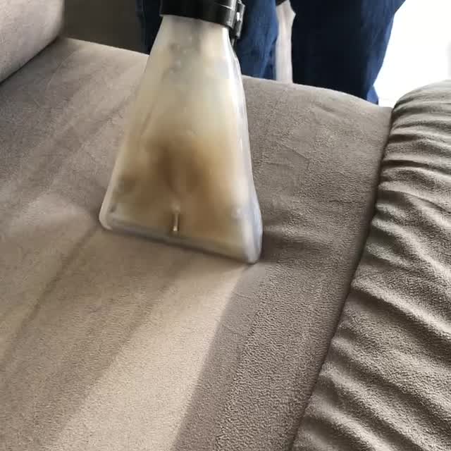 The clear extraction nozzle moving across a sofa seat and pulling out the dirty water.
