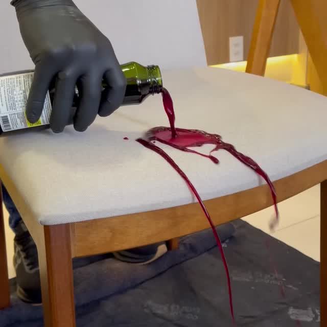 Doctor Couch technician wearing a mask, goggles, gloves and foot protection, cleaning the cushions of a light-colored sofa.